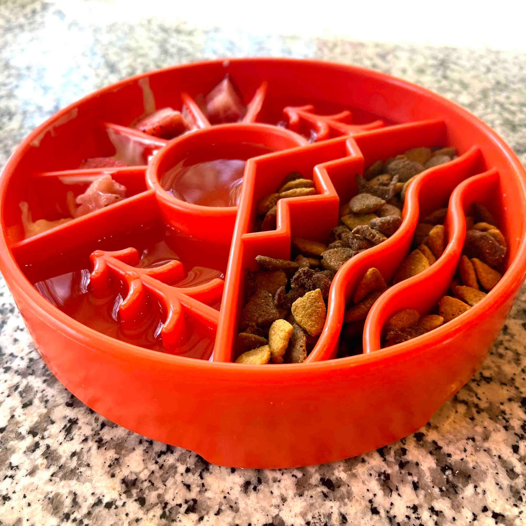 Orange puzzle slow feeder with pet food on a granite surface