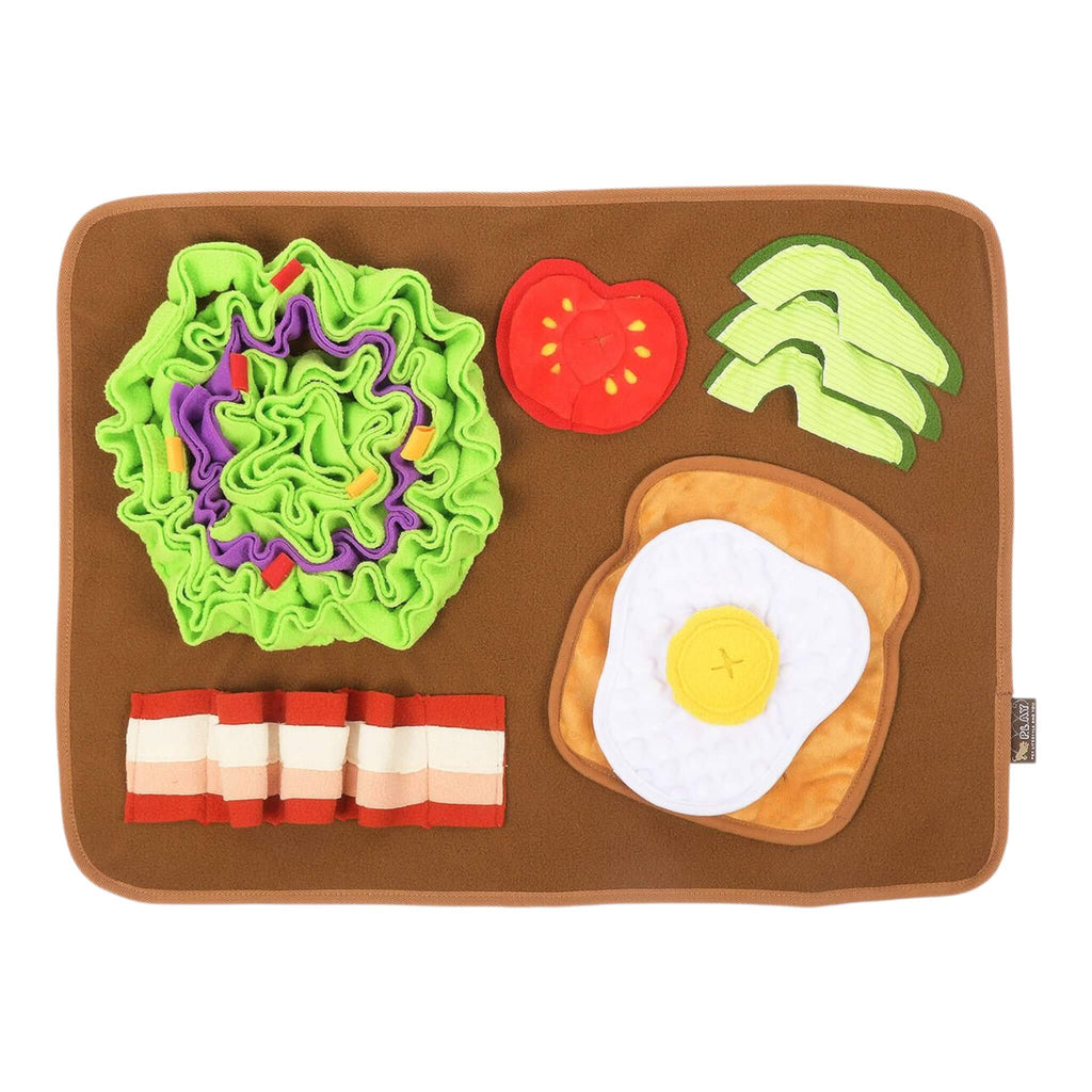 Dog snuffle mat with toy food items including tomato, avocado, bacon, and egg on a brown background.