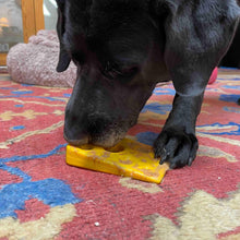 Load image into Gallery viewer, Dog licks up peanut butter from his Swiss Cheese Wedge ChewToy
